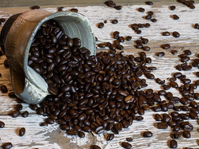 A spill of coffee beans from a coffee cup on its side 